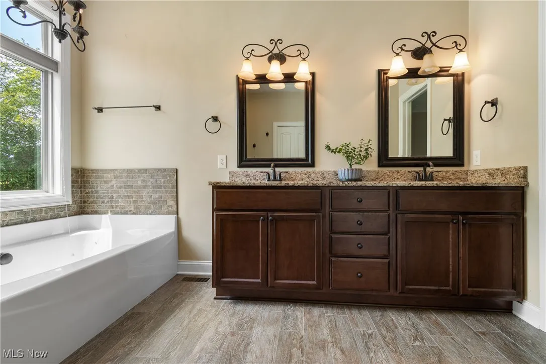 Full bath featuring double vanity, wood finished floors, and a garden tub