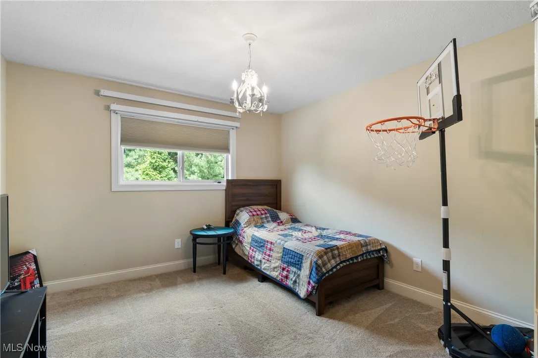 Carpeted bedroom featuring a chandelier and baseboards