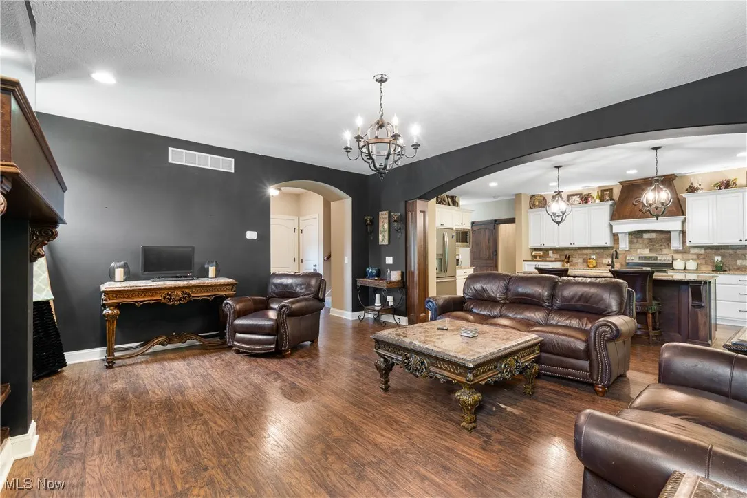 Living area featuring arched walkways, a chandelier, wood finished floors, and recessed lighting