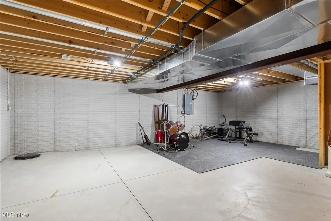 Unfinished basement featuring electric panel and brick wall