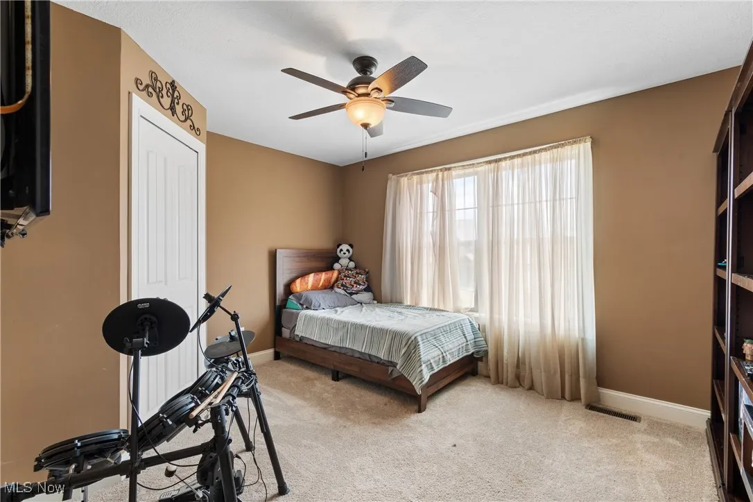 Bedroom featuring light colored carpet, a ceiling fan, and a closet