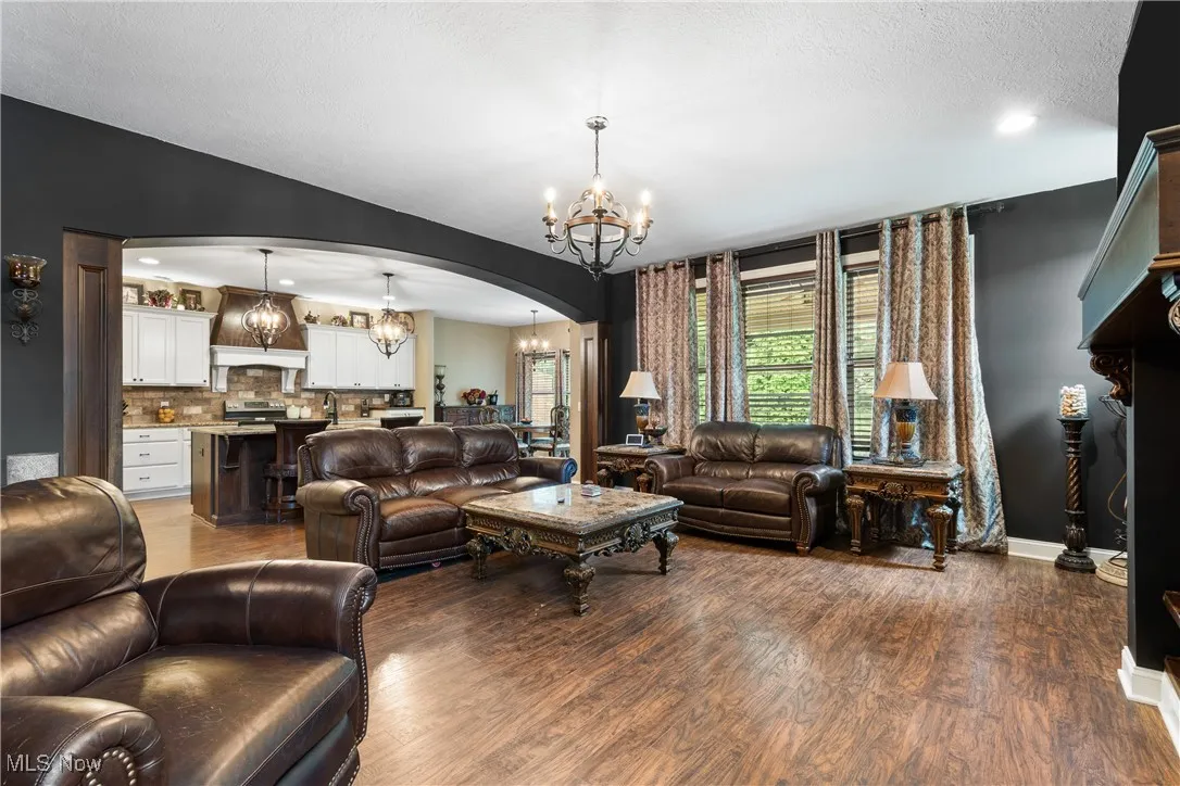 Living area featuring a chandelier, arched walkways, wood finished floors, and a textured ceiling
