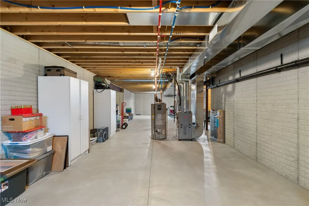 Unfinished basement featuring water heater and heating unit