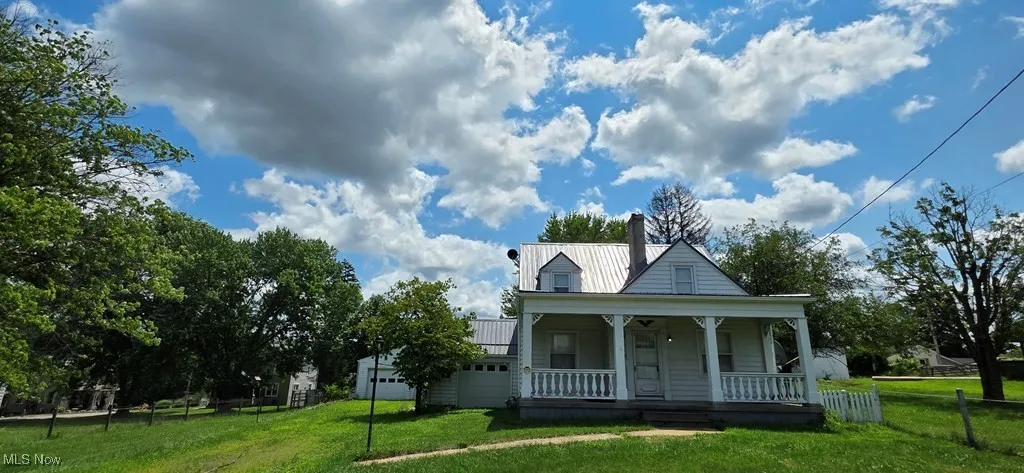 View of front of home with a porch, a metal roof, and a chimney