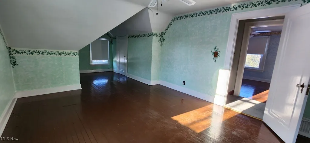Bonus room with hardwood / wood-style floors, wallpapered walls, a ceiling fan, and lofted ceiling