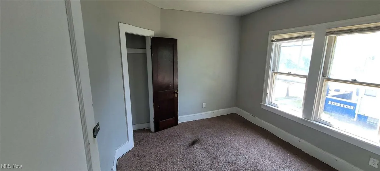 Unfurnished bedroom with dark carpet and multiple windows