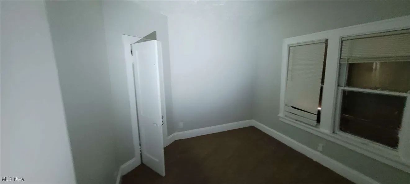 Unfurnished room featuring dark carpet and baseboards