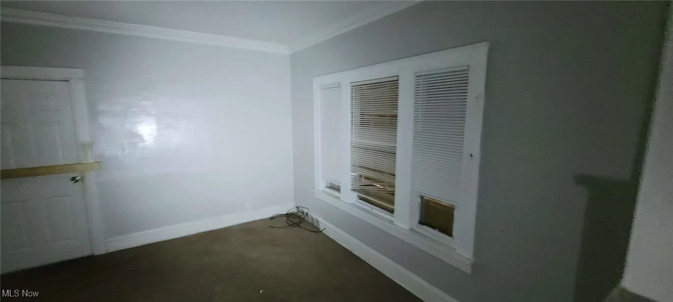 Empty room with crown molding and baseboards