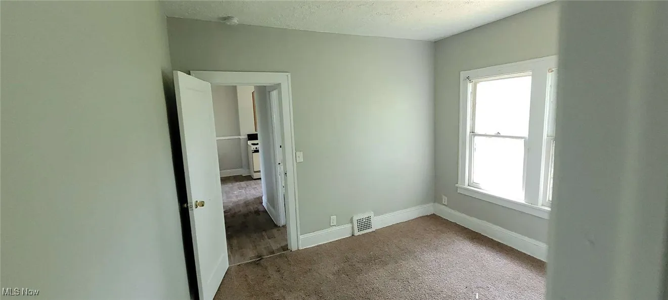 Unfurnished room featuring healthy amount of natural light, carpet flooring, and a textured ceiling