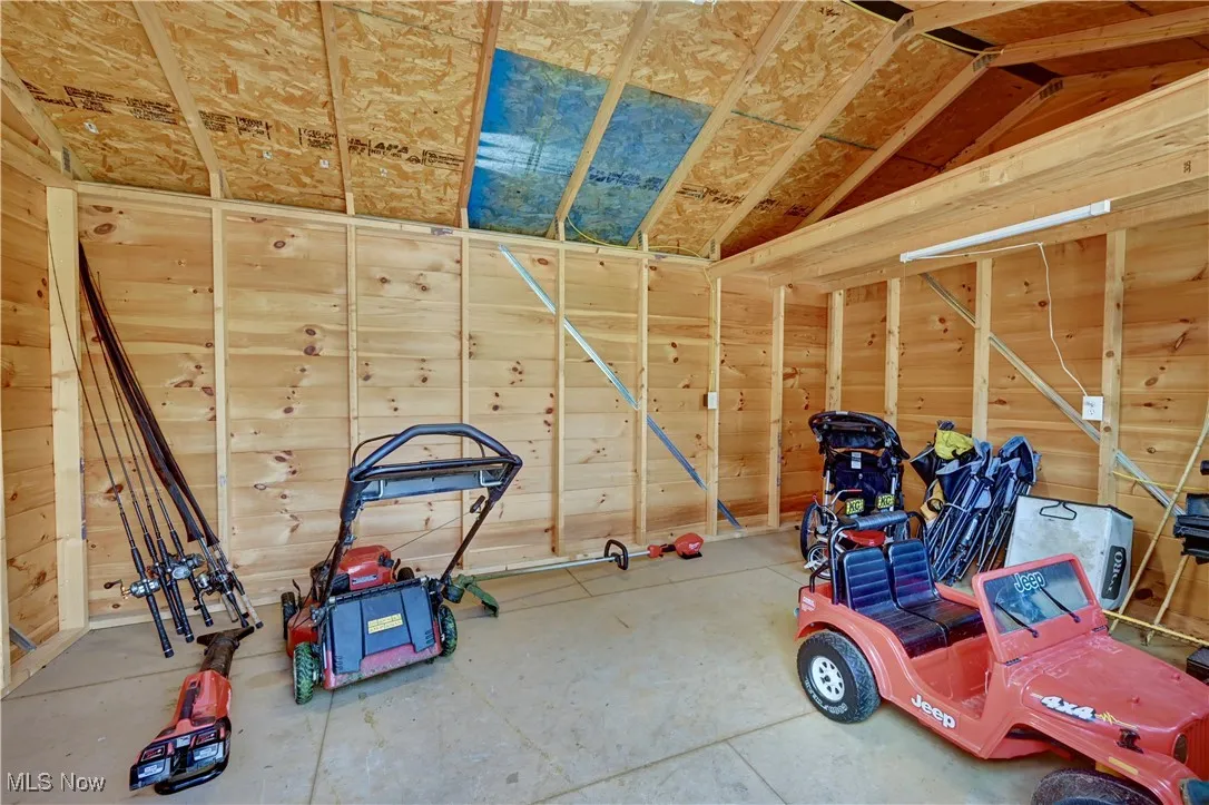 Miscellaneous room featuring lofted ceiling, wooden walls, and concrete floors