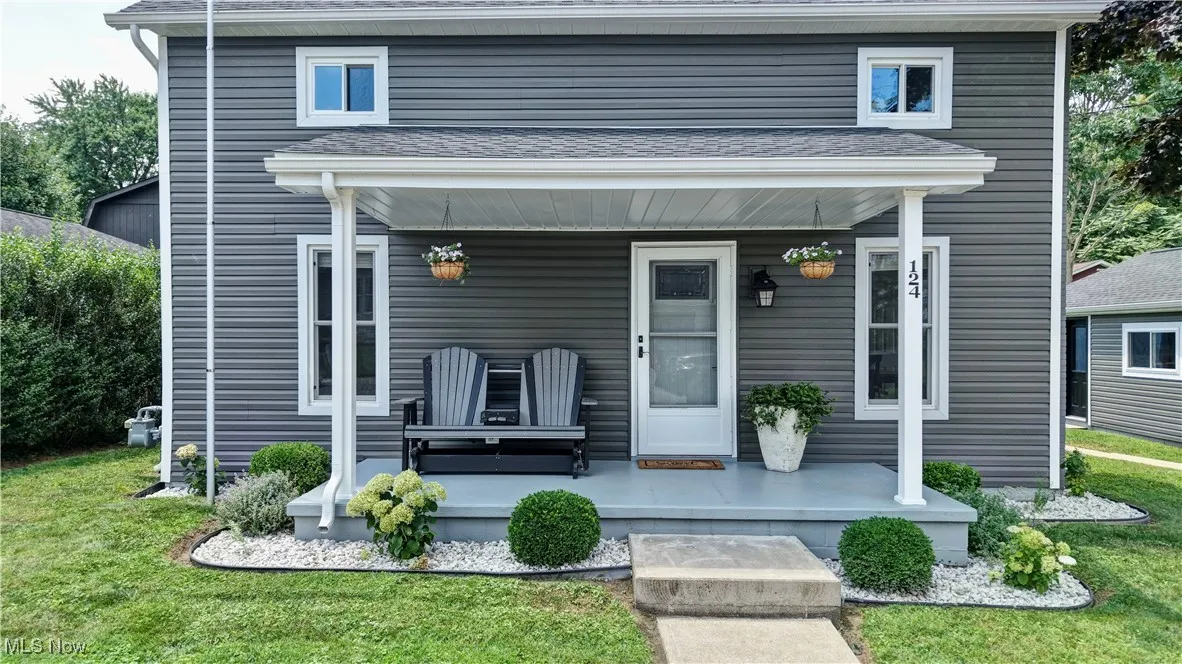 View of front of home with a porch, roof with shingles, and a front yard