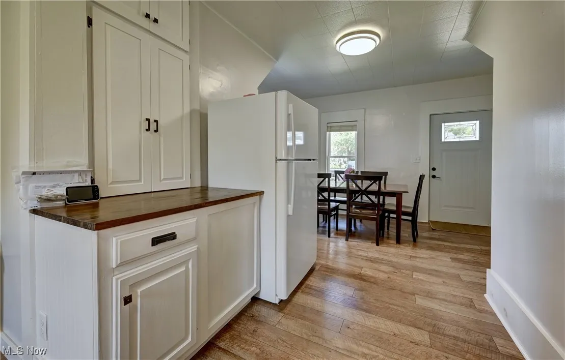 Kitchen featuring freestanding refrigerator, light wood finished floors, butcher block counters, and white cabinets