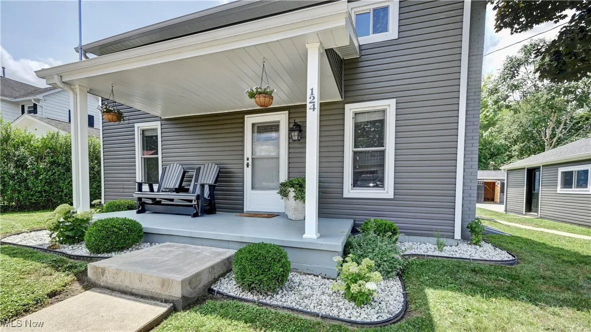 Entrance to property with covered porch and a yard