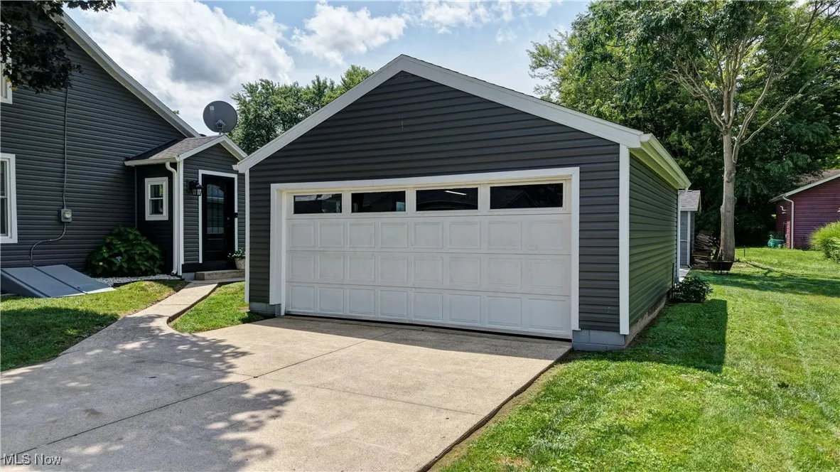 View of front of house with a garage, an outbuilding, driveway, and a front lawn