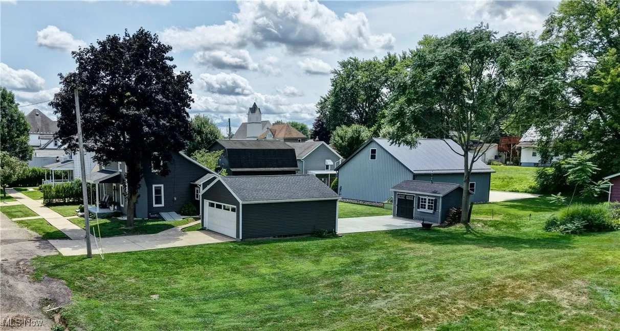 View of side of property with an outdoor structure, concrete driveway, a yard, and a residential view