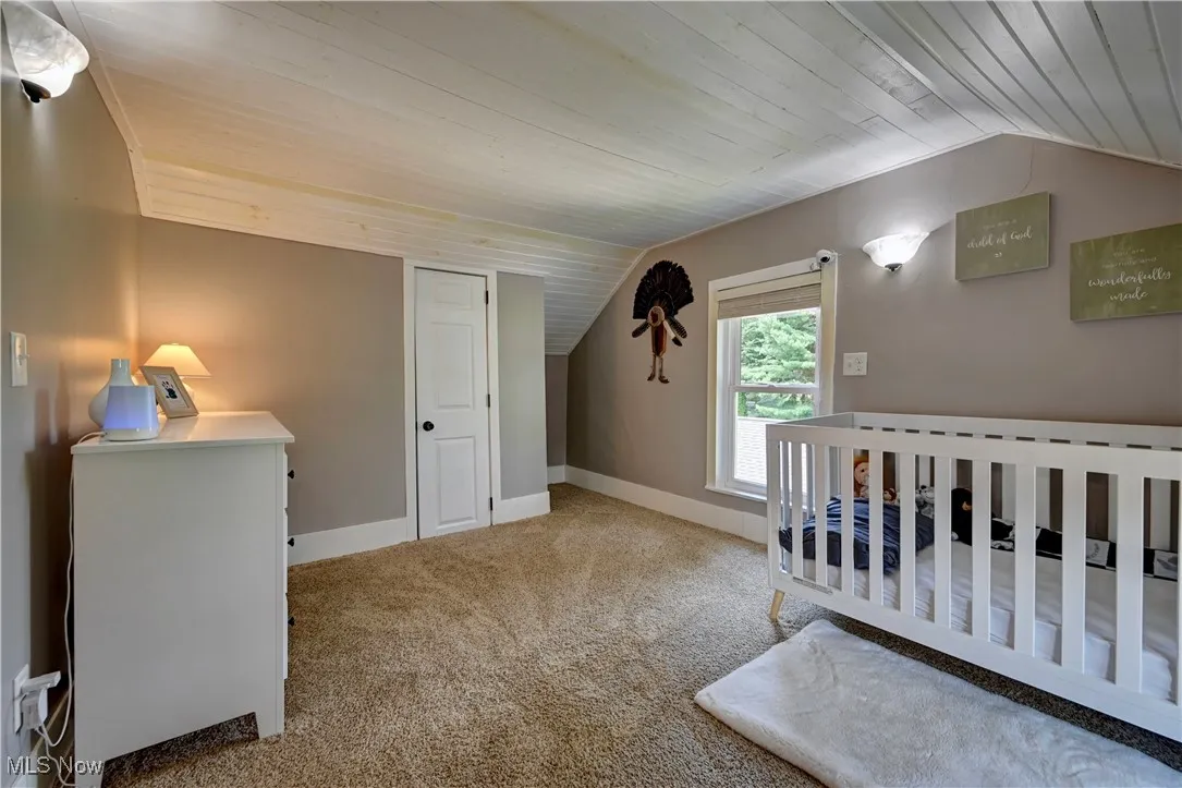 Carpeted bedroom featuring vaulted ceiling and wooden ceiling