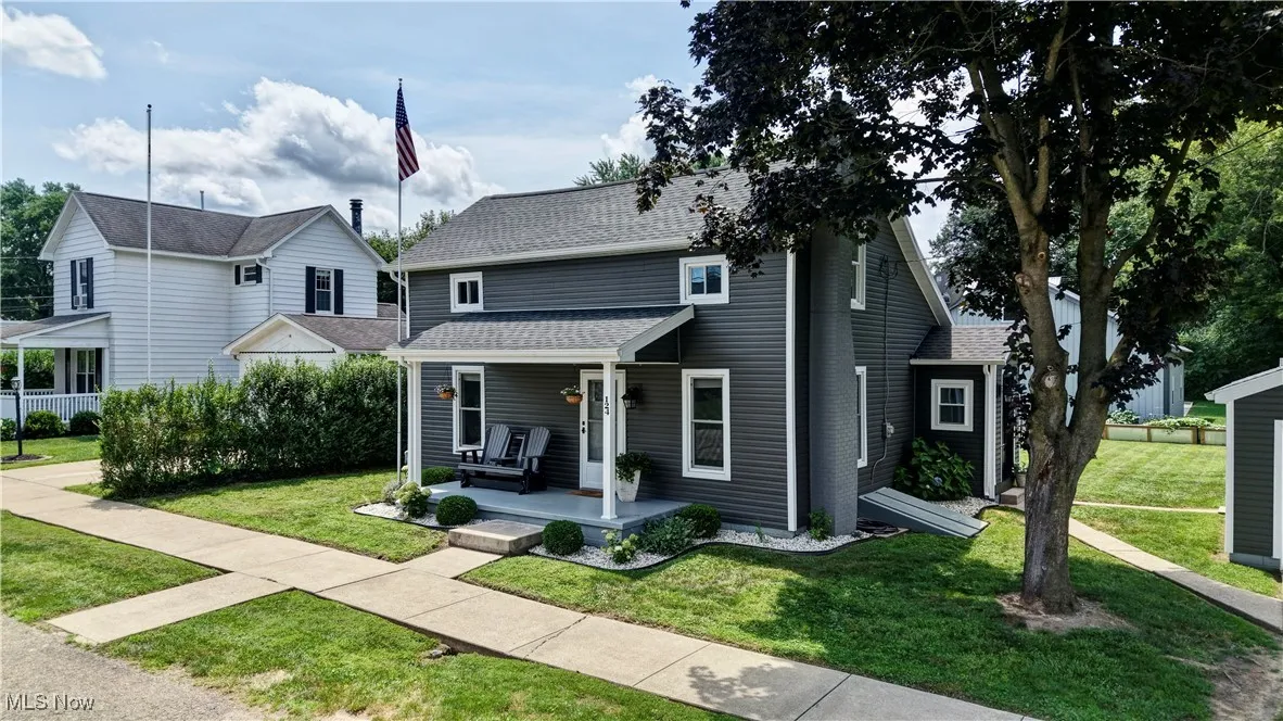 Traditional-style house featuring covered porch, a shingled roof, and a front yard