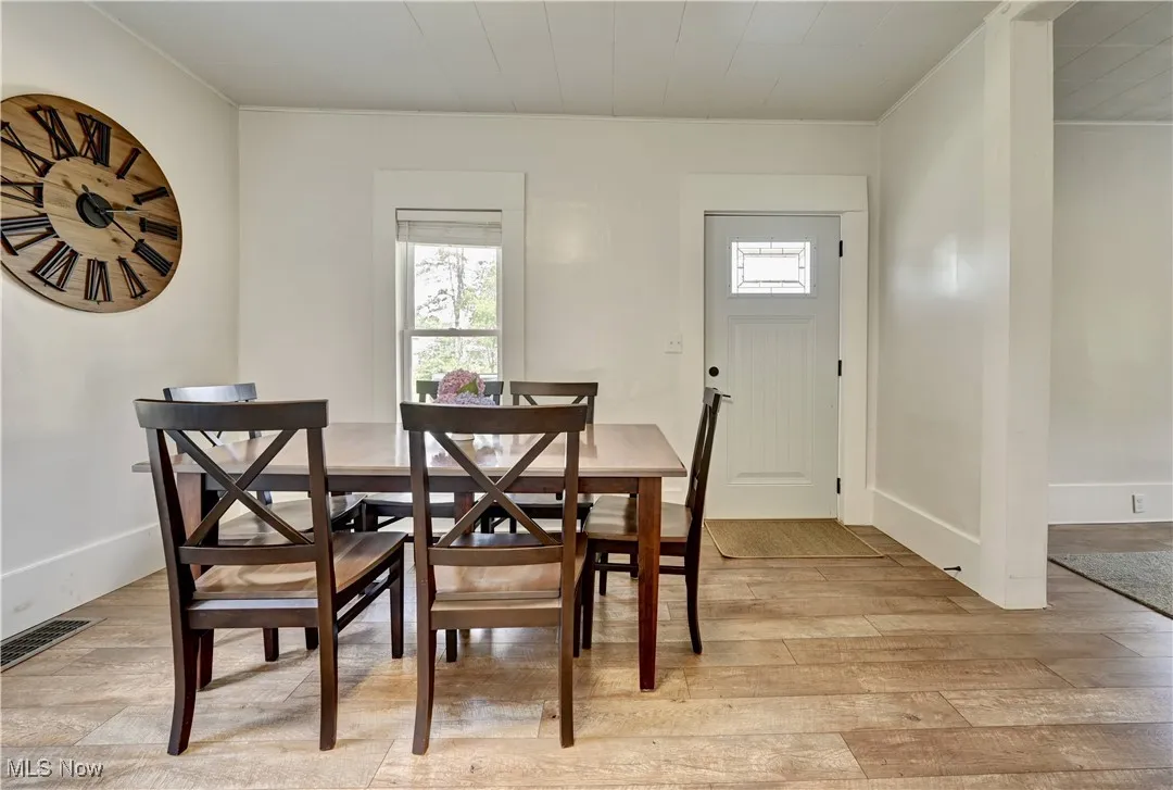 Dining space featuring healthy amount of natural light, light wood-type flooring, and crown molding