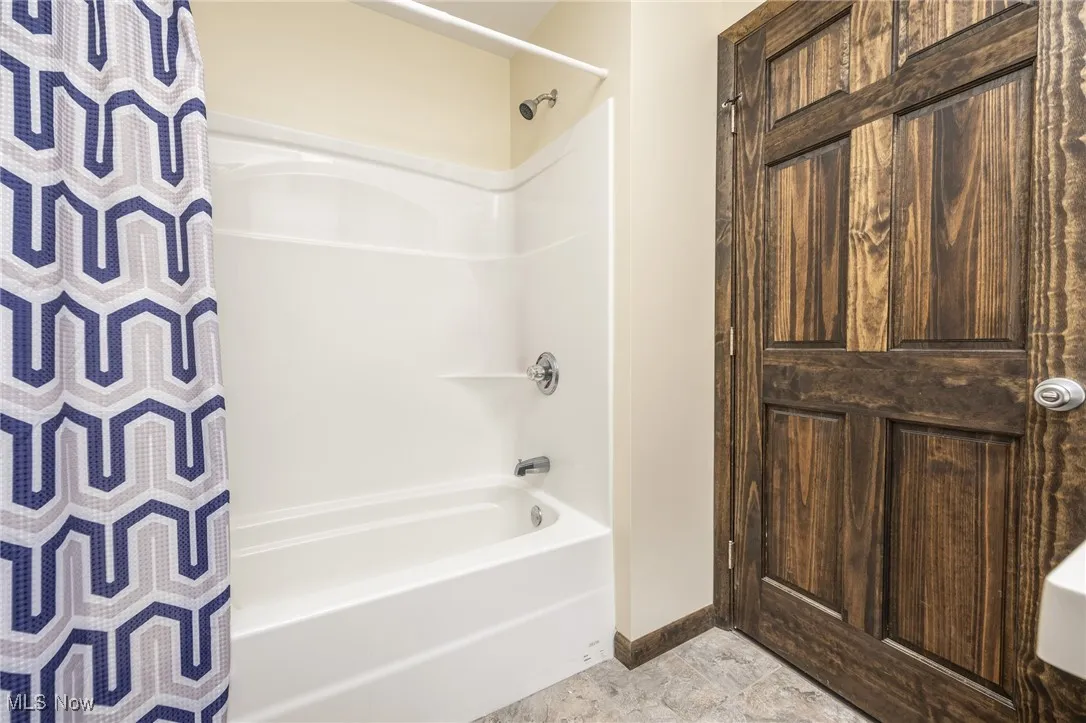 Full bathroom with shower / bath combo with shower curtain and baseboards