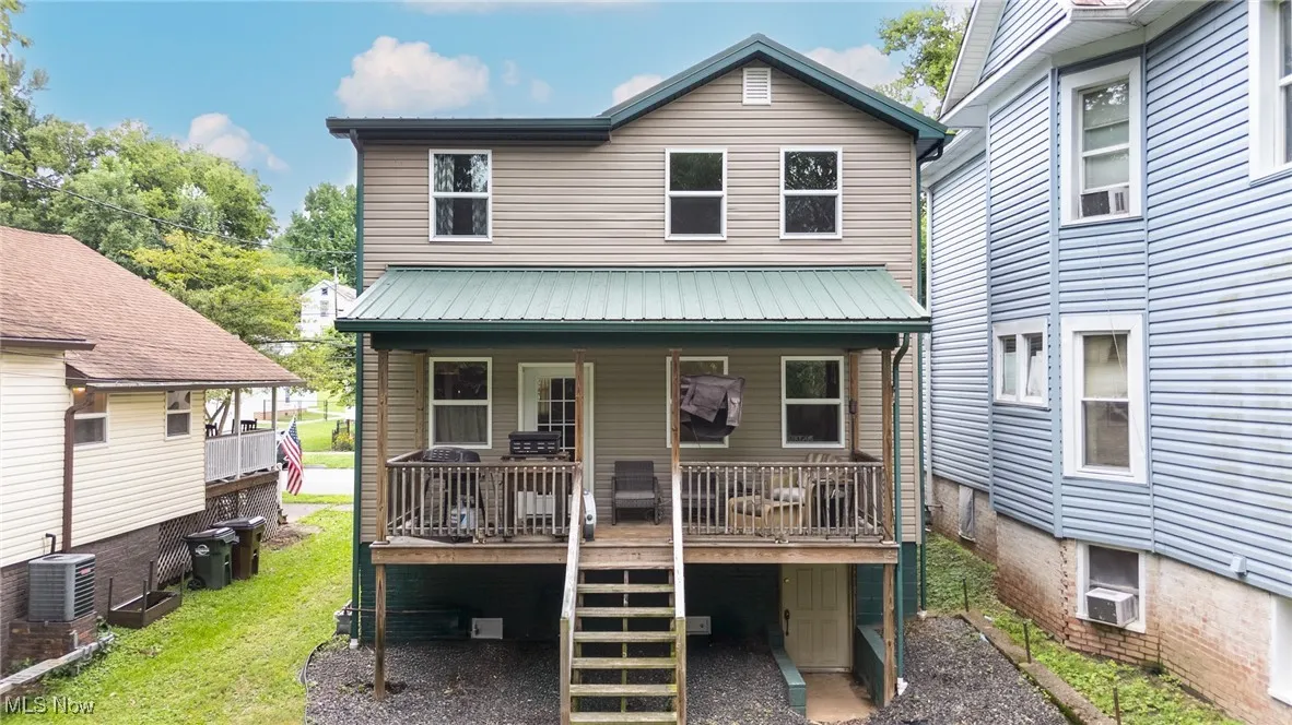 Rear view of house with a metal roof, stairway, and cooling unit