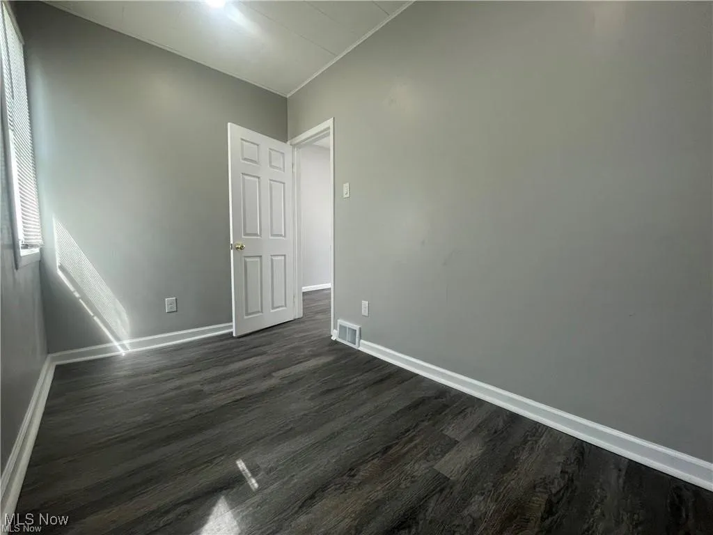 Unfurnished room with dark wood-style floors and baseboards