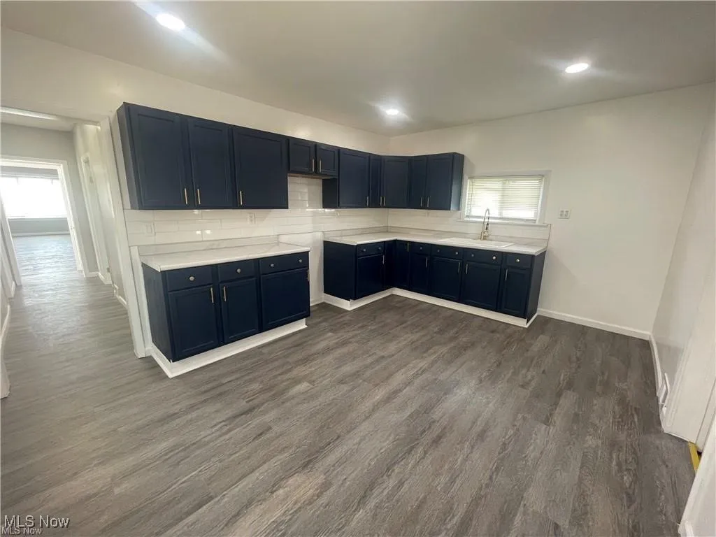 Kitchen with dark wood-style flooring, backsplash, light countertops, and recessed lighting