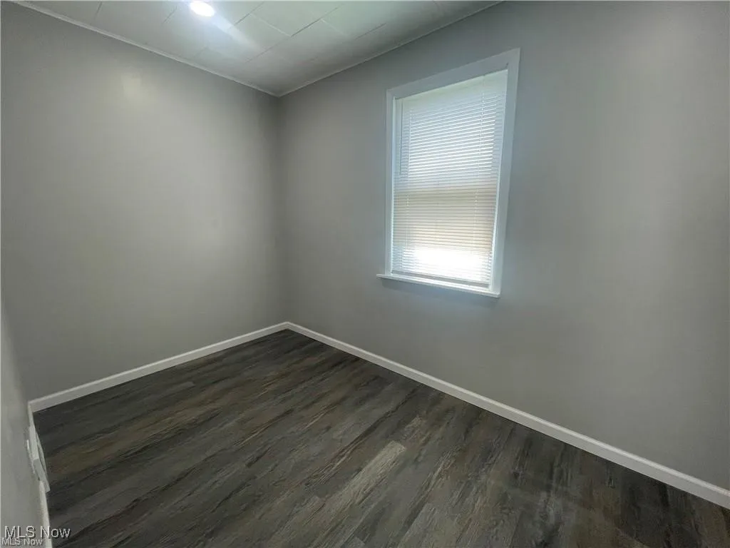 Unfurnished room featuring baseboards and dark wood finished floors