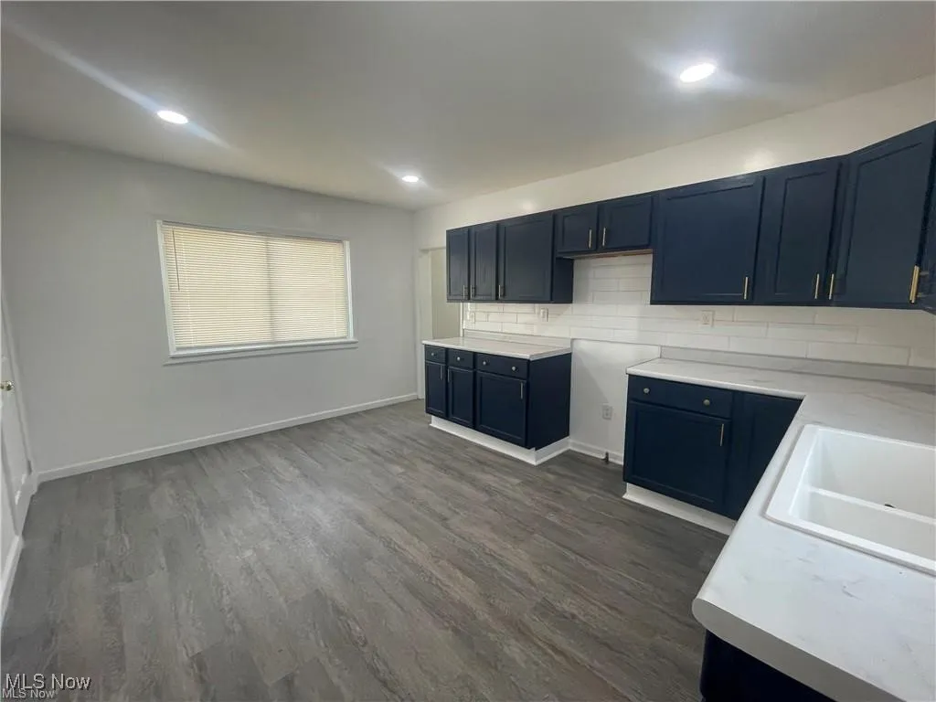 Kitchen with dark wood-type flooring, backsplash, light countertops, and recessed lighting