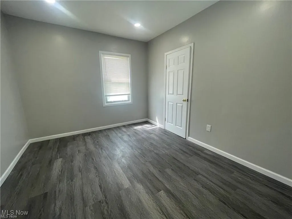 Empty room with dark wood-type flooring and recessed lighting