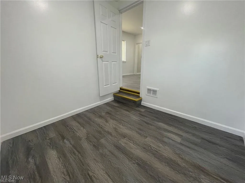 Unfurnished room with dark wood finished floors and baseboards
