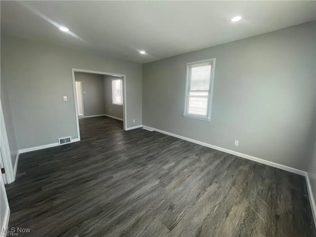 Empty room with dark wood-type flooring and recessed lighting