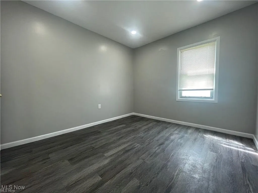 Unfurnished room with baseboards and dark wood finished floors