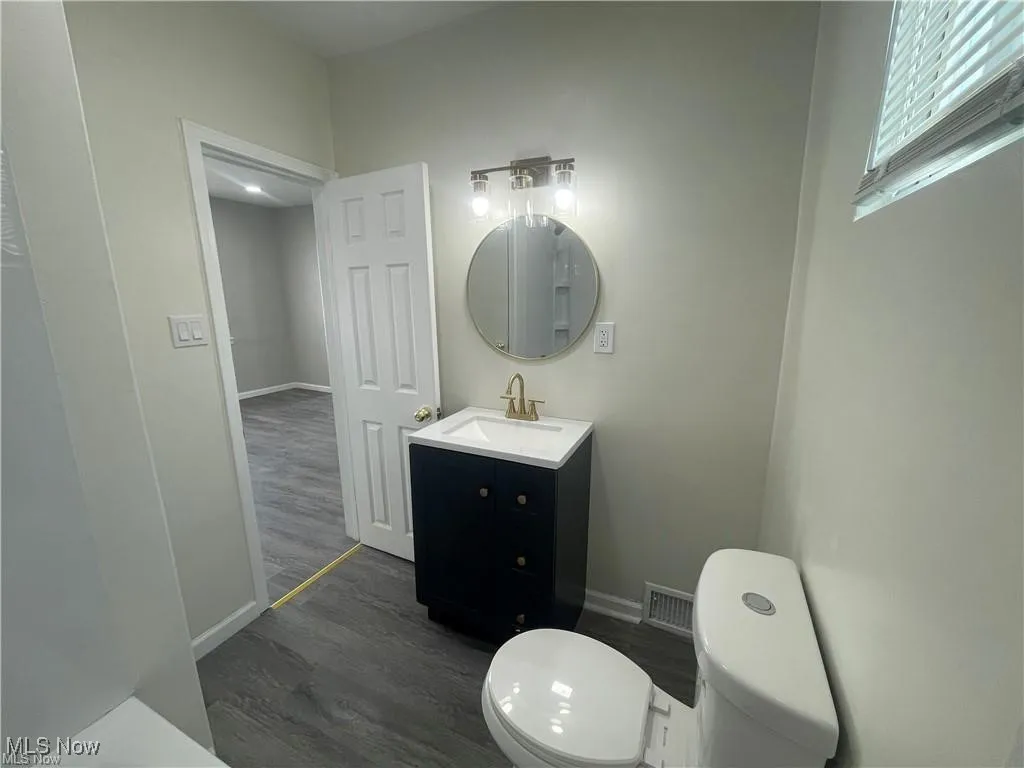 Half bathroom featuring wood finished floors and vanity
