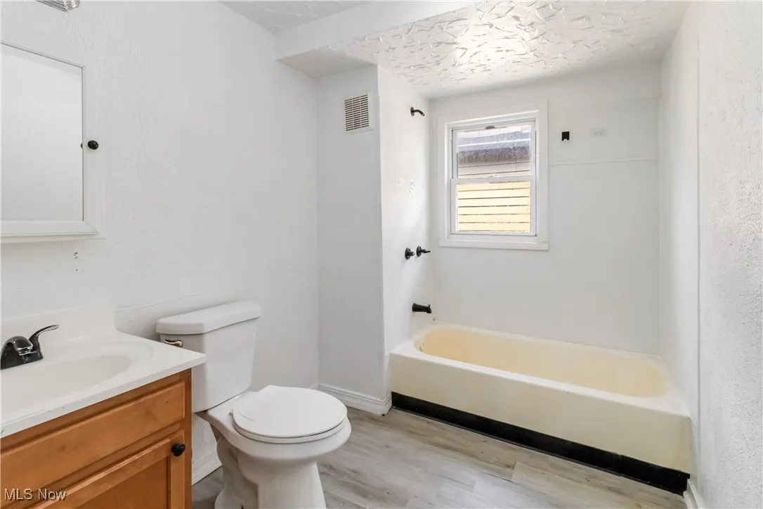 Full bath featuring wood finished floors, a bathtub, vanity, and a textured ceiling