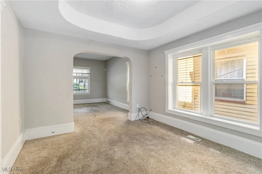 Carpeted spare room featuring arched walkways and baseboards