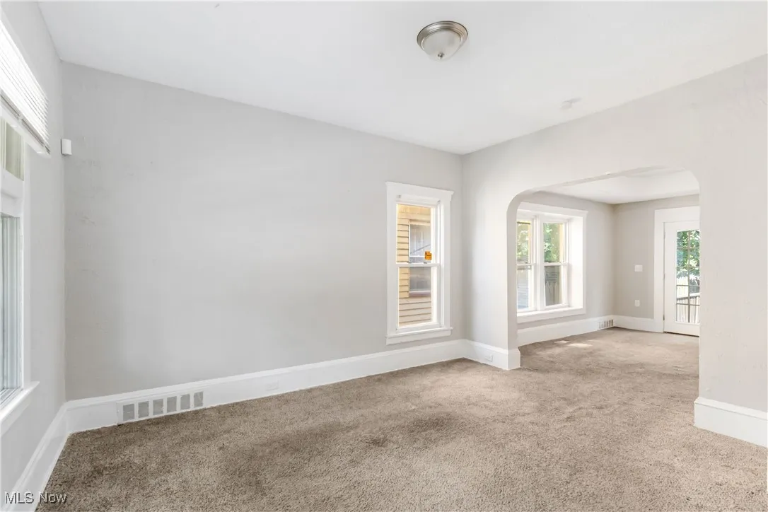 Empty room featuring arched walkways and carpet floors