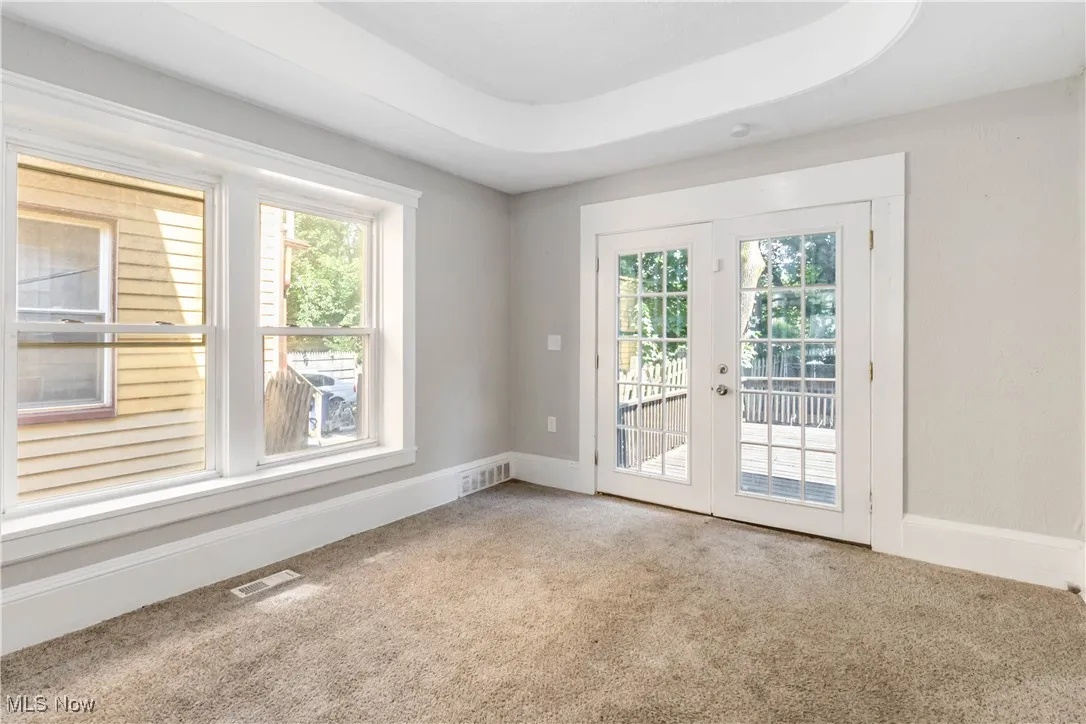 Empty room featuring carpet floors, healthy amount of natural light, and french doors