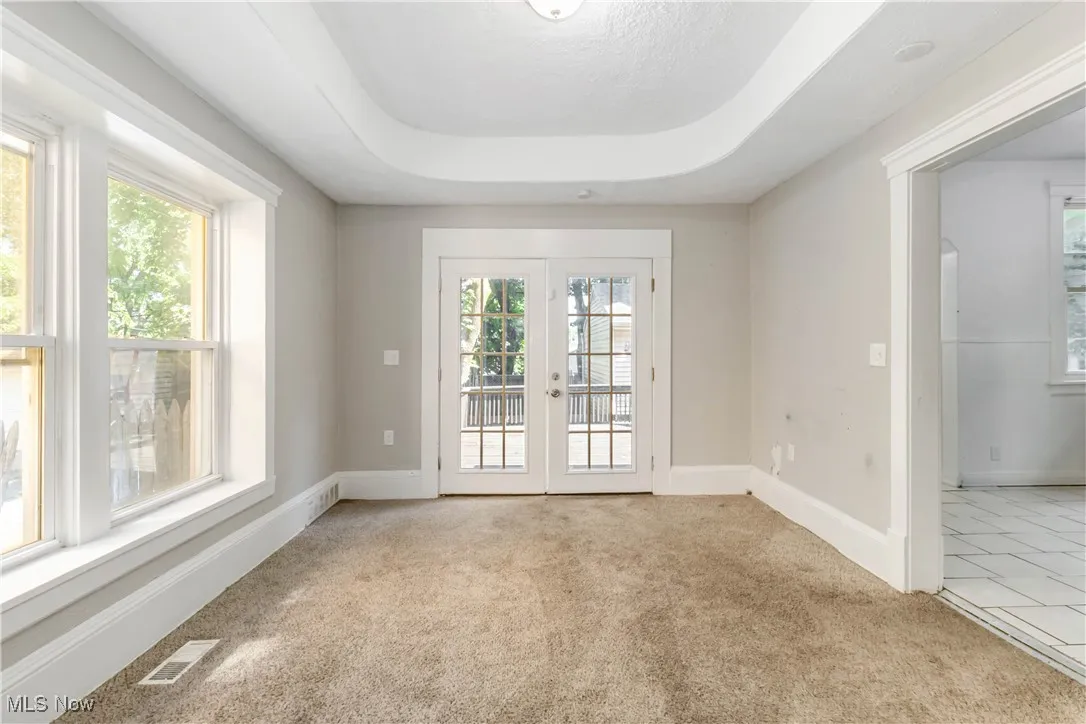 Unfurnished room featuring french doors and light colored carpet