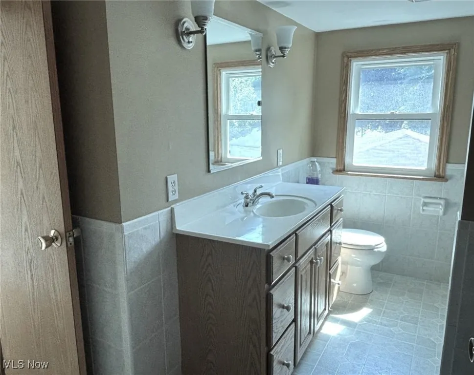 Main Bathroom on second floor with tile walls, vanity, wainscoting, and tile patterned flooring
