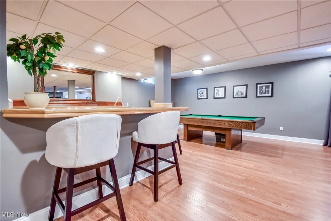 Rec room featuring billiards table, wood finished floors, a drop ceiling, recessed lighting, and bar