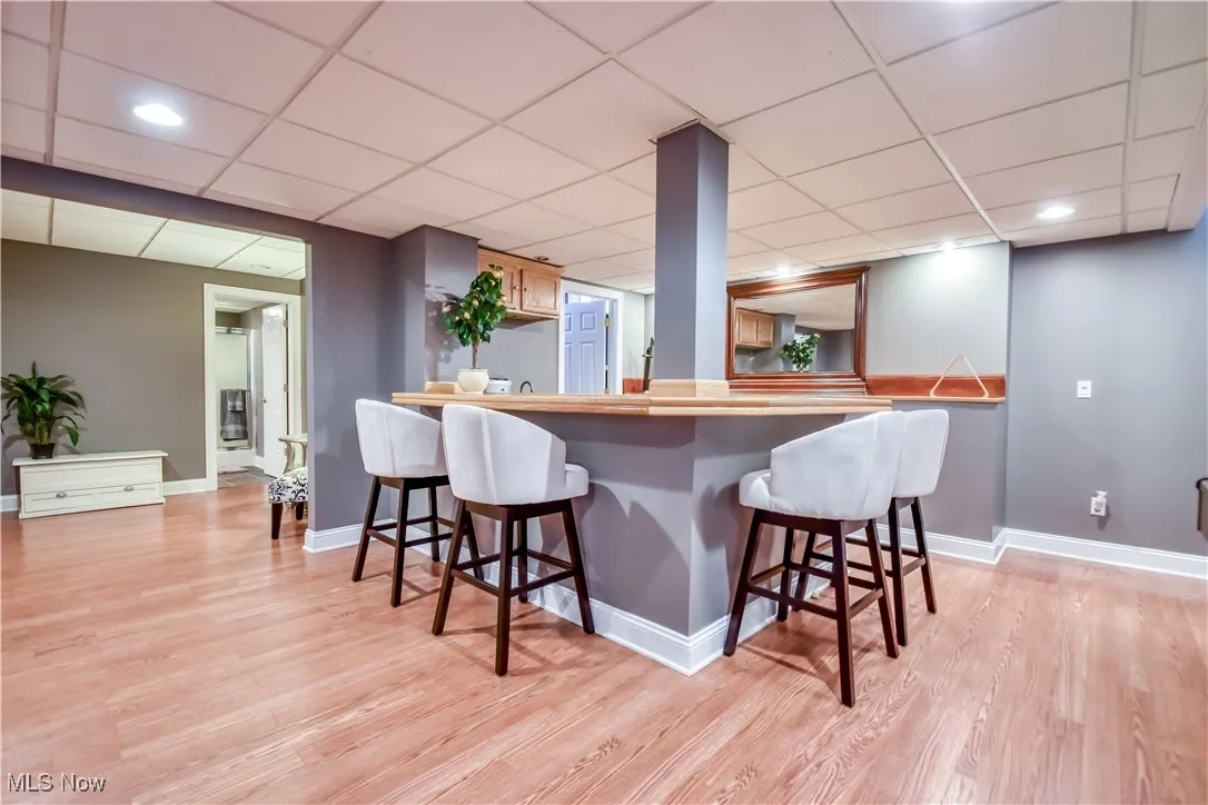 Kitchen featuring a kitchen breakfast bar, light wood finished floors, a paneled ceiling, and recessed lighting