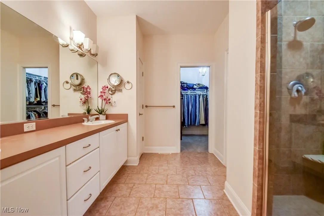 Full bathroom featuring vanity, a walk in closet, a shower stall, and tile patterned flooring