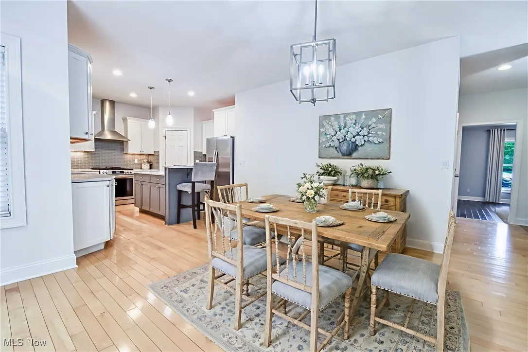 Dining area with light wood-style flooring, recessed lighting, and a chandelier - virtually staged