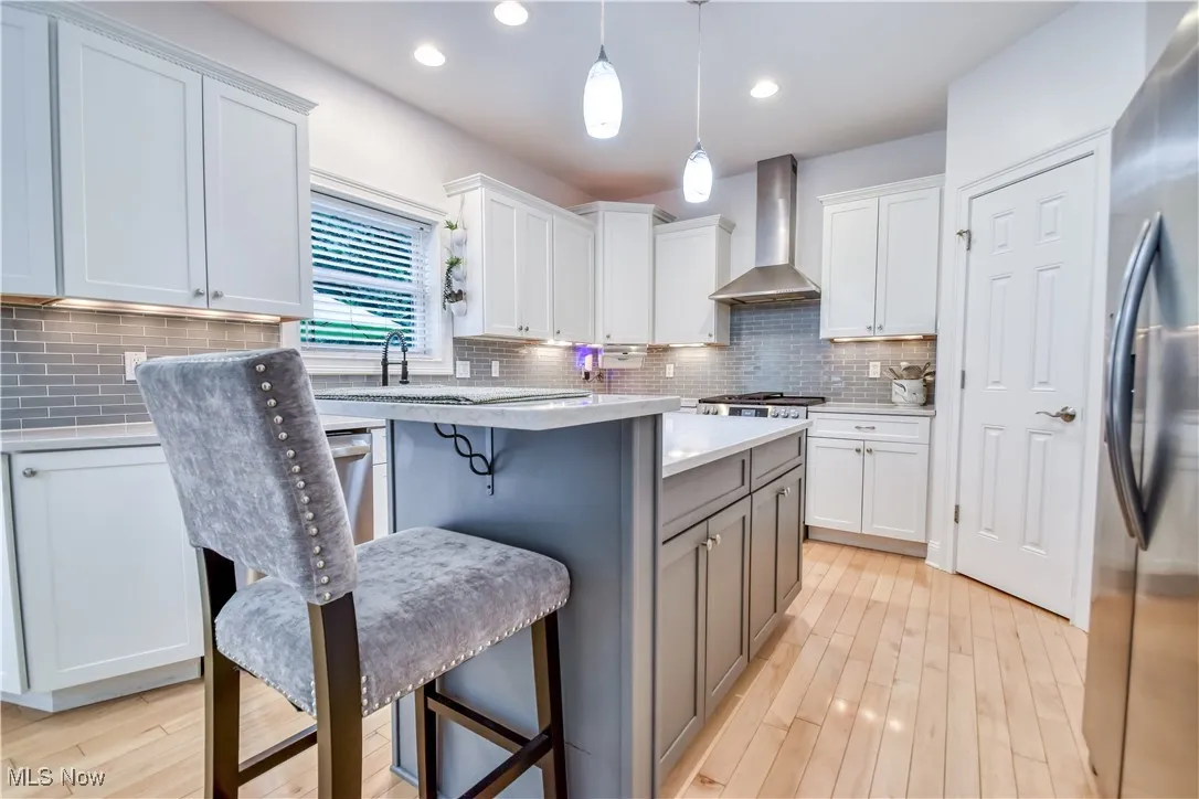 Kitchen featuring light countertops, a breakfast bar area, freestanding refrigerator, light wood-type flooring, and decorative backsplash