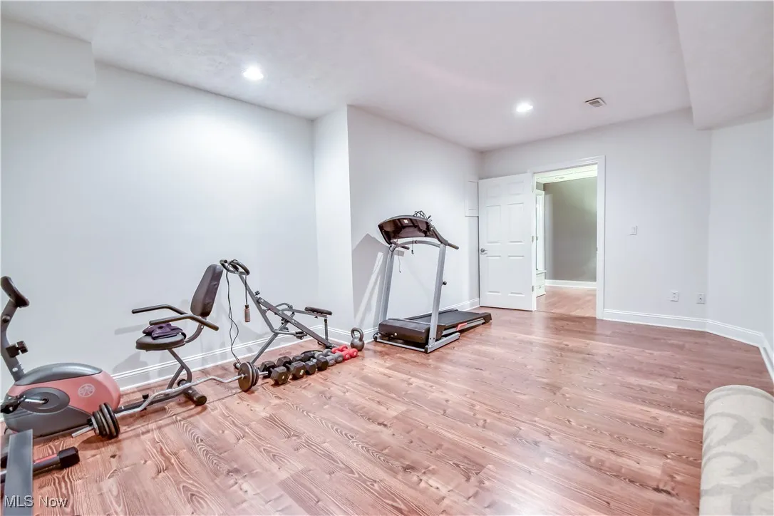 Workout room with wood finished floors and recessed lighting
