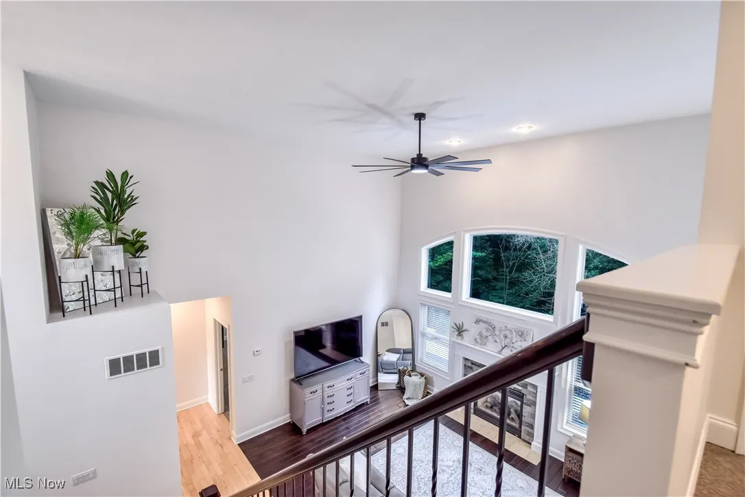 Stairs with wood finished floors and ceiling fan