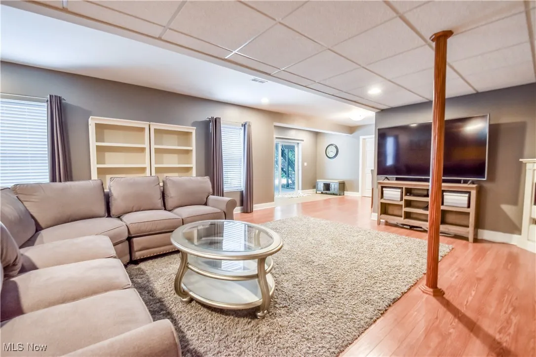 Living area with a drop ceiling, wood finished floors, and recessed lighting