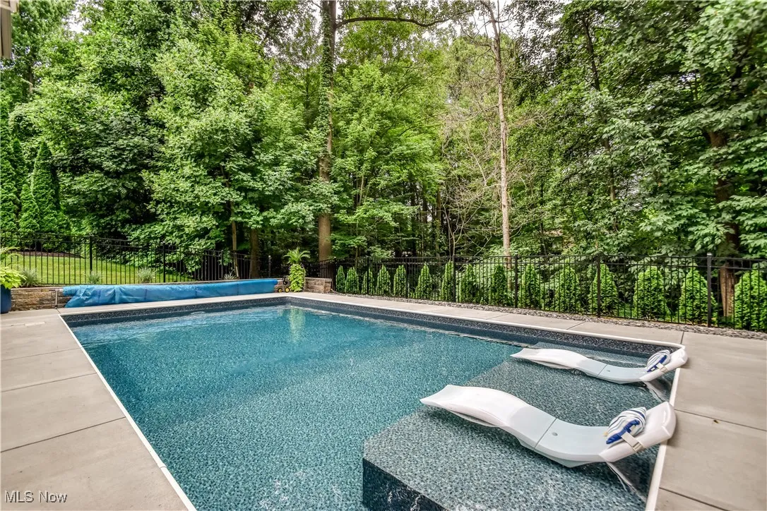 View of pool with a fenced backyard and a forest view