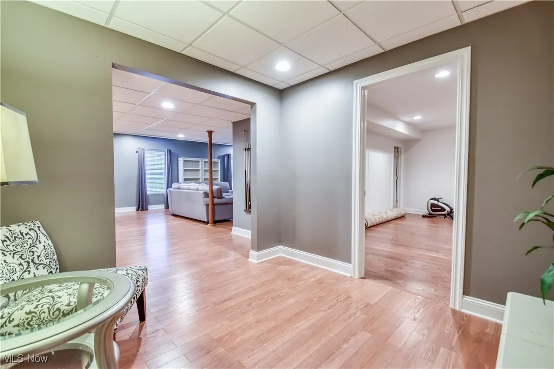 Hall with a paneled ceiling, light wood-style floors, and recessed lighting