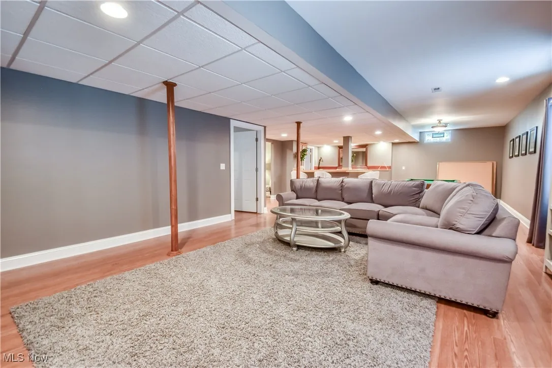 Living room with wood finished floors, recessed lighting, and bar area